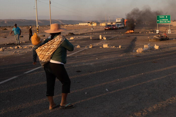 Fotografía de archivo en la que se captó a un una mujer con un niño a su espalda al caminar por la carretera que une los países de Perú y Chile, en Tacna (Perú). EFE/Rafael Arancibia
