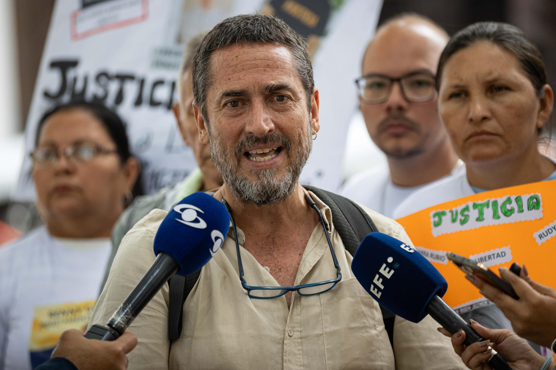 El activistas de Derechos Humanos, Antonio González (c), habla durante una rueda de prensa este jueves, frente al Ministerio Público, en Caracas (Venezuela). Familiares de presos políticos protestan frente al Ministerio Público para exigir la liberación de los presos acusados por terrorismo y vinculados con las Tancol, acrónimo acuñado por las autoridades venezolanas para referirse a 'terroristas armados narcotraficantes colombianos'. EFE/ Ronald Peña R
