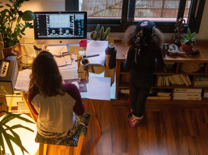 En la imagen de archivo, una mujer realiza teletrabajo en su casa mientras su hija juega a su lado. EFE/Enric Fontcuberta
