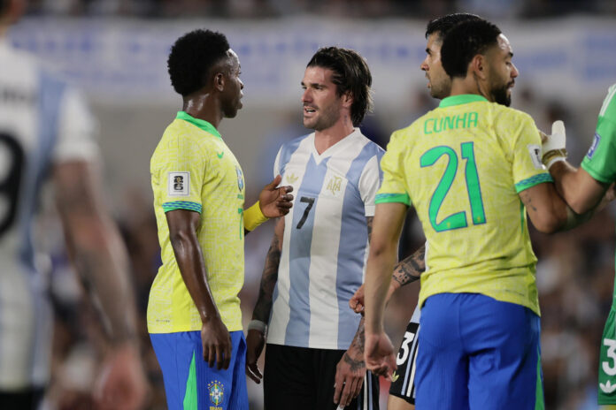 Rodrigo De Paul (c) de Argentina habla con Vinícius Júnior (i) de Brasil durante un partido de las eliminatorias sudamericanas para el Mundial de 2026. EFE/ Luciano González
