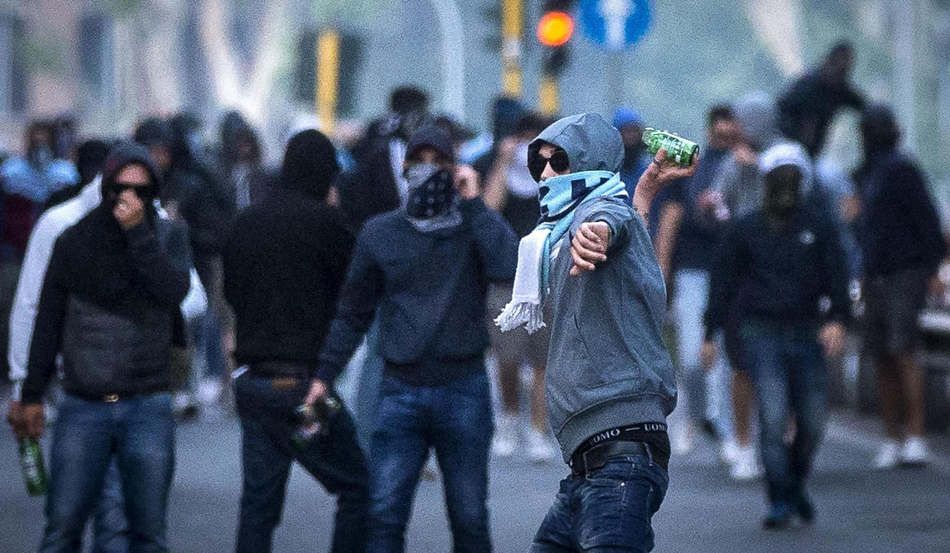 Fotografía de Angelo Carconi, en la que puede verse en una imagen de archivo del 25 de mayo de 2015 a aficionados del Lazio lanzando botellas de vidrio a la policía. EFE
