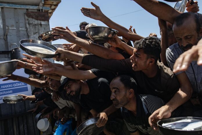 Palestinos desplazados sostienen ollas y sartenes de metal mientras se reúnen para recibir comidas calientes de una cocina benéfica en Jan Yunis, sur de la Franja de Gaza, 04 de junio de 2026. La distribución de alimentos se produjo en medio de severas escaseces de suministros básicos de ayuda en todo el enclave. Agencias de la ONU informaron que a pesar de un alto el fuego nominal, la entrada de ayuda crítica a Gaza sigue estando fuertemente restringida. EFE/EPA/HAITHAM IMAD
