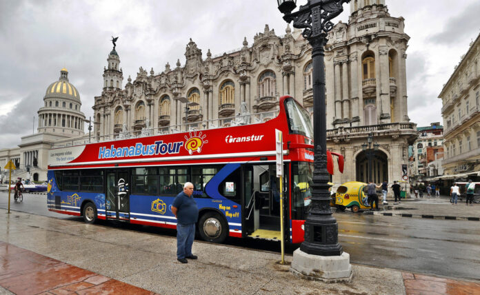 Fotografía de archivo del conductor de un bus turístico a la espera de visitantes en La Habana (Cuba). EFE/Ernesto Mastrascusa
