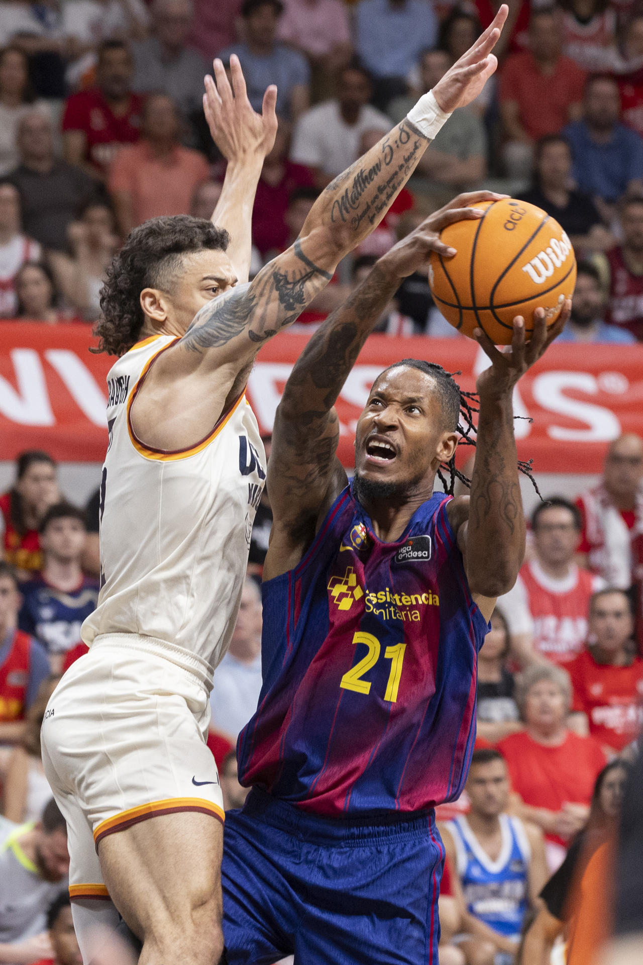 El alero del Barcelona Will Clyburn (d) intenta encestar ante la presión del base estadounidense de UCAM Murcia Jonah Radebaugh (i), durante el tercer partido de cuartos de final de la Liga Endesa que Barcelona y UCAM Murcia están disputando este sábado en el Palacio de los Deportes de Murcia. EFE/Marcial Guillén
