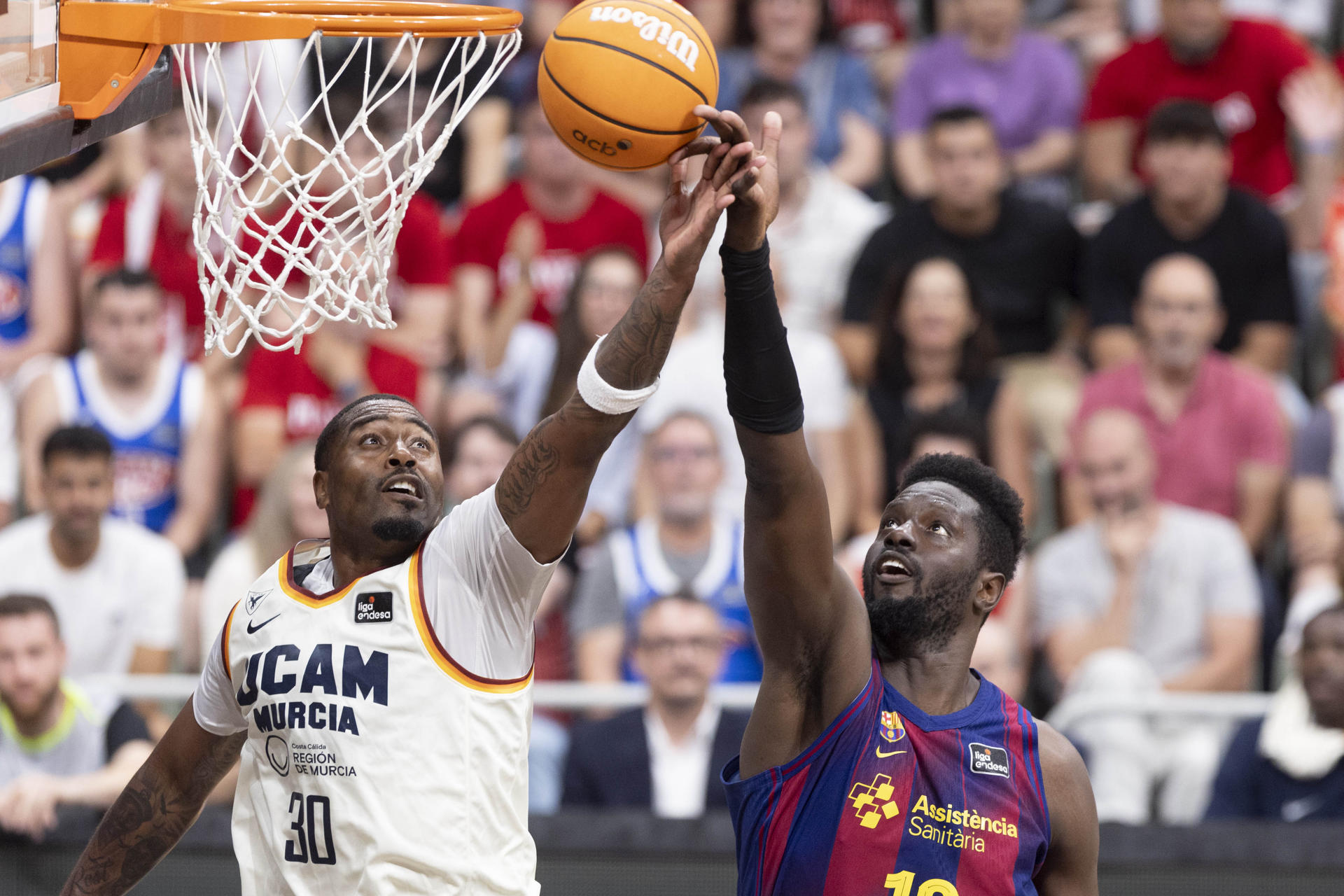 El ala pívot estadounidense de UCAM Murcia Kelan Martin (i) intenta controlar el balón ante la presión del pívot francés del F.C. Barcelona Fall (d), durante el tercer partido de cuartos de final de la Liga Endesa que Barcelona y UCAM Murcia están disputando este sábado en el Palacio de los Deportes de Murcia. EFE/Marcial Guillén