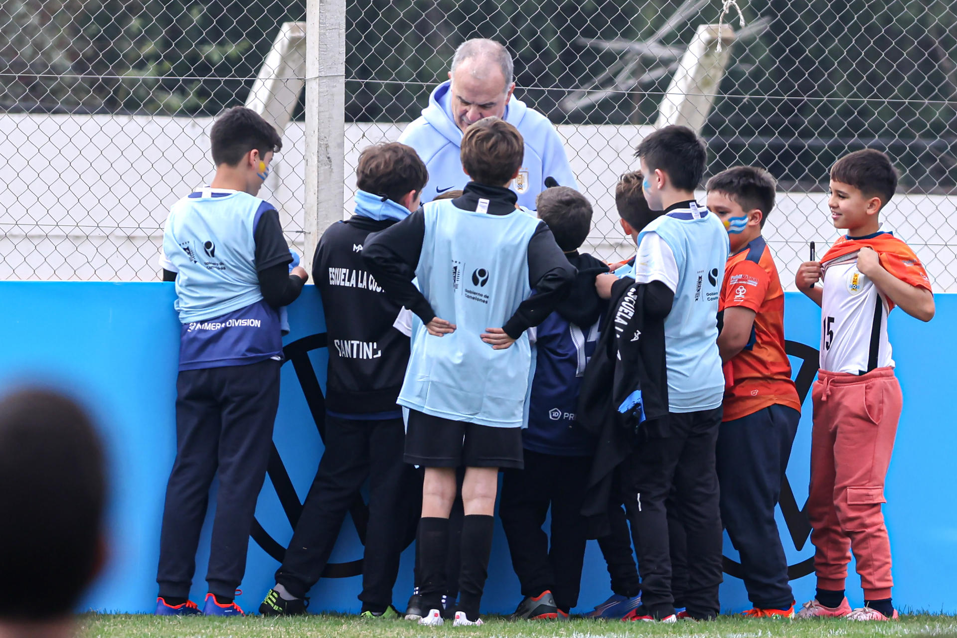 Fotografía de Gaston Britos, en la que puede verse en una imagen del 5 de junio al seleccionador de fútbol de Uruguay, el argentino Marcelo Bielsa, conversando con niños durante un evento de despedida en Pando, Canelones (Uruguay). EFE
