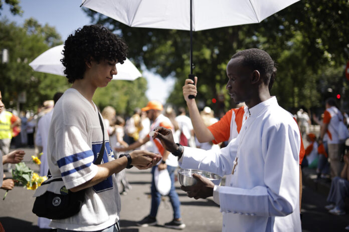 Sacerdotes voluntarios dan la eucaristía durante la misa del Corpus Christi oficiada por papa León XIV este domingo en Madrid. EFE/ Marcos Villaoslada
