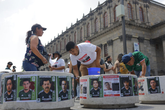 Fotografía del 31 de mayo de 2026, de personas pegando fichas de búsqueda de desaparecidos en el centro histórico de la ciudad de Guadalajara (México). EFE/ Francisco Guasco
