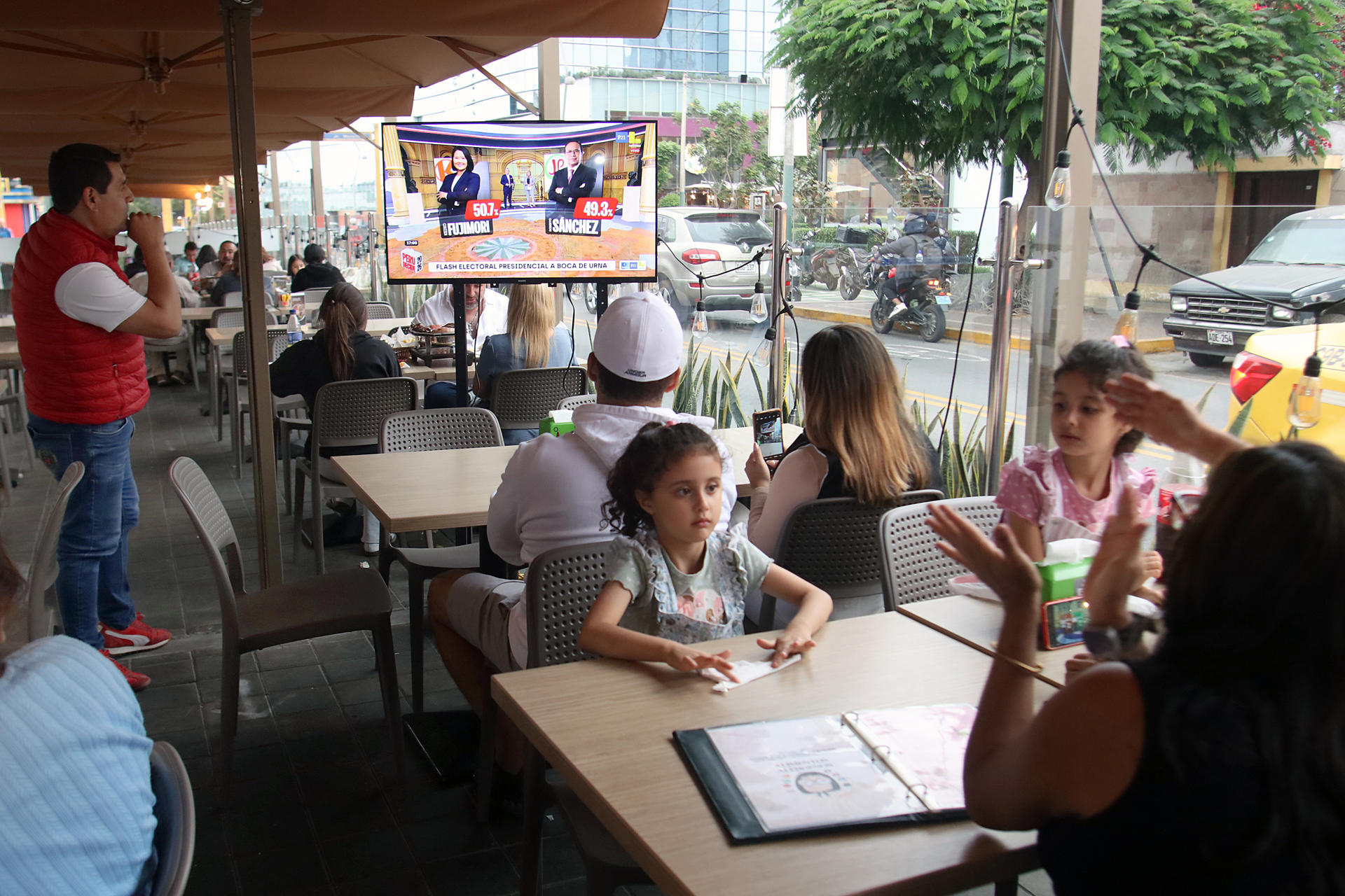 Personas observa en un televisor los sondeos a pie de urna durante la segunda vuelta de las elecciones presidenciales de Perú donde dan un empate técnico entre la derechista Keiko Fujimori y el izquierdista Roberto Sánchez este domingo, en San Borja, en Lima (Perú). EFE/ Paul Vallejos