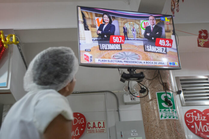 Una persona fue captada este 7 de junio al observar en un televisor los resultados de los sondeos a pie de urna, tras el cierre de los colegios electorales de la segunda vuelta de las elecciones presidenciales de Perú, donde dan un empate técnico entre la derechista Keiko Fujimori y el izquierdista Roberto Sánchez, en Lima (Perú). EFE/Renato Pajuelo
