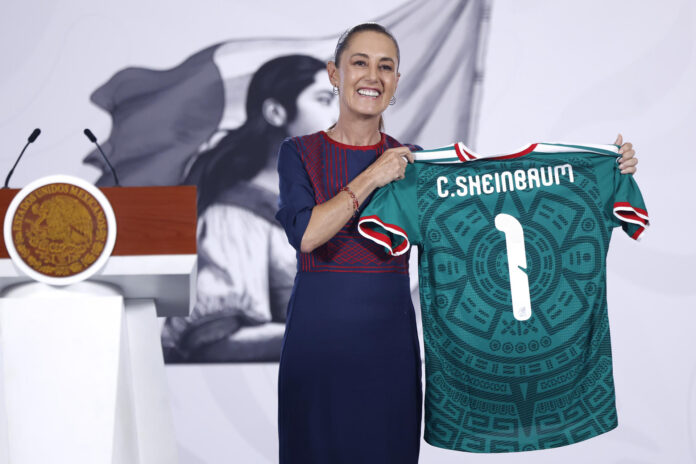 La presidenta de México, Claudia Sheinbaum, posa con una camiseta de la selección de México este lunes, durante una rueda de prensa en el Palacio Nacional de Ciudad de México (México). EFE/ Sáshenka Gutiérrez
