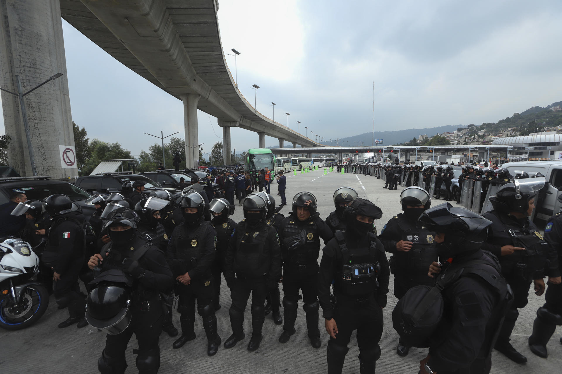 Integrantes de la Secretaría de Seguridad de México bloquean el paso de buses donde viajan estudiantes de Ayotzinapan que se dirigen al Zócalo para manifestarse junto a la Coordinación Nacional de Trabajadores de la Educación (CNTE) este lunes, en el peaje de Tlalpan, al sur de la Ciudad de México (México). EFE/ Madla Hartz
