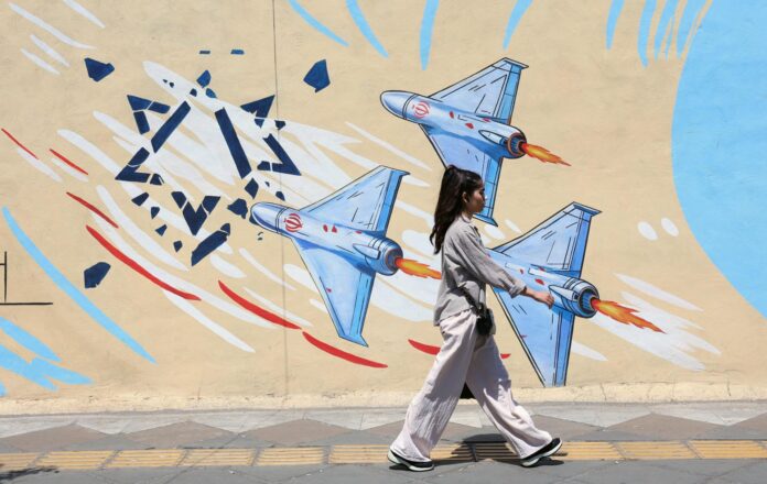 Una joven iraní pasa junto a un mural antiisraelí en una calle de Teherán, Irán, el lunes 8 de junio. EFE/EPA/ABEDIN TAHERKENAREH RESTRICCIONES: Prohibido el acceso a medios de comunicación israelíes/canales de televisión en persa fuera de Irán/Prohibido el acceso a BBC Persian/VOA Persian/Manoto TV/Televisión Internacional de Irán. (Según lo dispuesto por la Dirección General de Medios de Comunicación Extranjeros de Irán)
