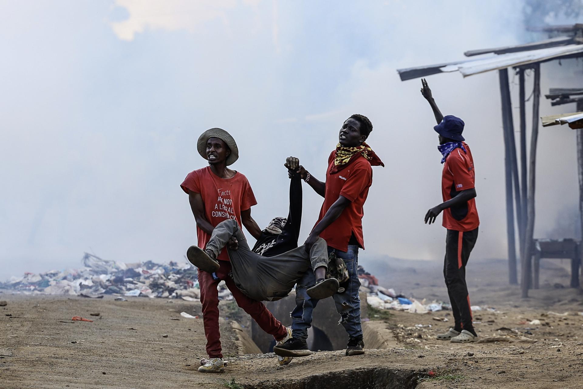 - Manifestantes buscan ayuda para un manifestante herido mientras el gas lacrimógeno inunda la zona durante una protesta contra una instalación de ébola en Nanyuki, Kenia, 09 de junio de 2026. Activistas de derechos humanos salieron a las calles para oponerse al establecimiento de un centro de cuarentena de ébola para ciudadanos estadounidenses en la Base Aérea de Laikipia. Una orden del Tribunal Superior había detenido temporalmente el establecimiento y funcionamiento de la instalación, mientras que informes señalaban que los preparativos continuaban después de que el Secretario del Gabinete de Salud, Aden Duale, defendiera el proyecto como parte de la estrategia de preparación de Kenia para el ébola. (Protestas, Kenia) EFE/EPA/DANIEL IRUNGU