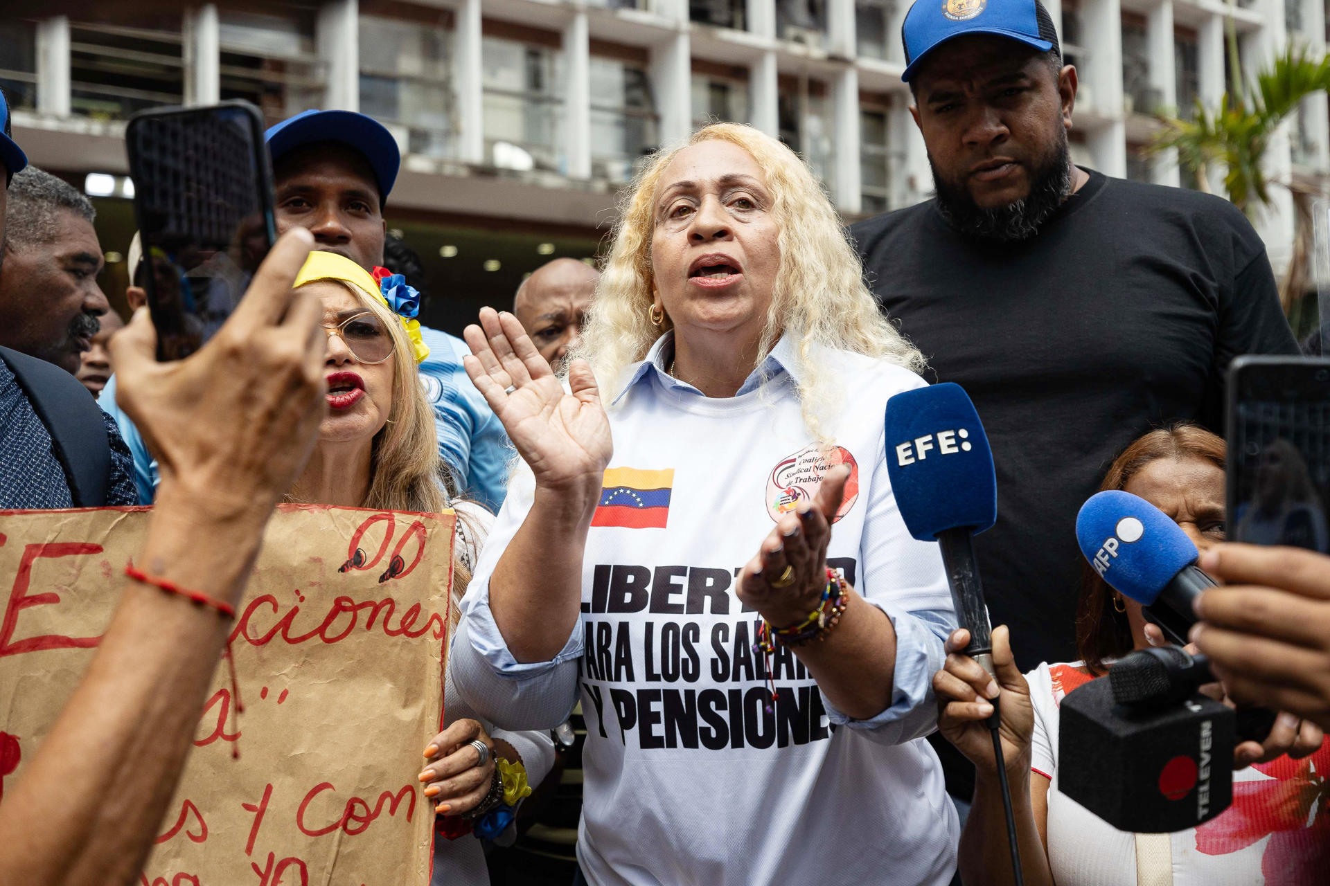 La integrante de la coalición sindical Estela Romero (c) habla con periodistas, durante una protesta de sindicalistas a las afueras del Consejo Nacional Electoral este martes, en Caracas (Venezuela). EFE/ Ronald Peña

