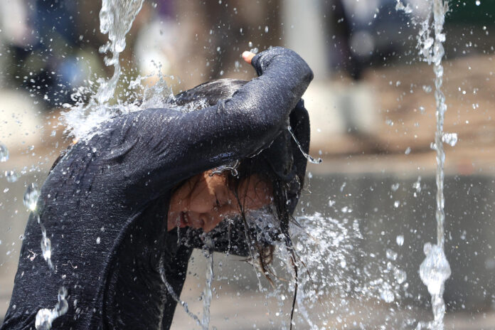 Imagen de archivo de un niño que se refresca en una fuente durante una de calor en San Salvador que generó 