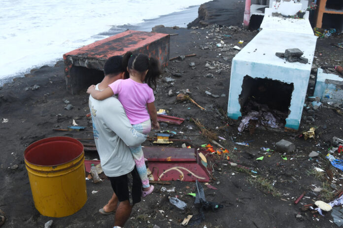 Una persona camina entre las tumbas destruidas del cementerio general de la Aldea Conacaste debido al fuerte oleaje y constantes lluvias generadas por la tormenta tropical Cristina este miércoles, en el puerto de Iztapa (Guatemala). EFE/ Alex Cruz
