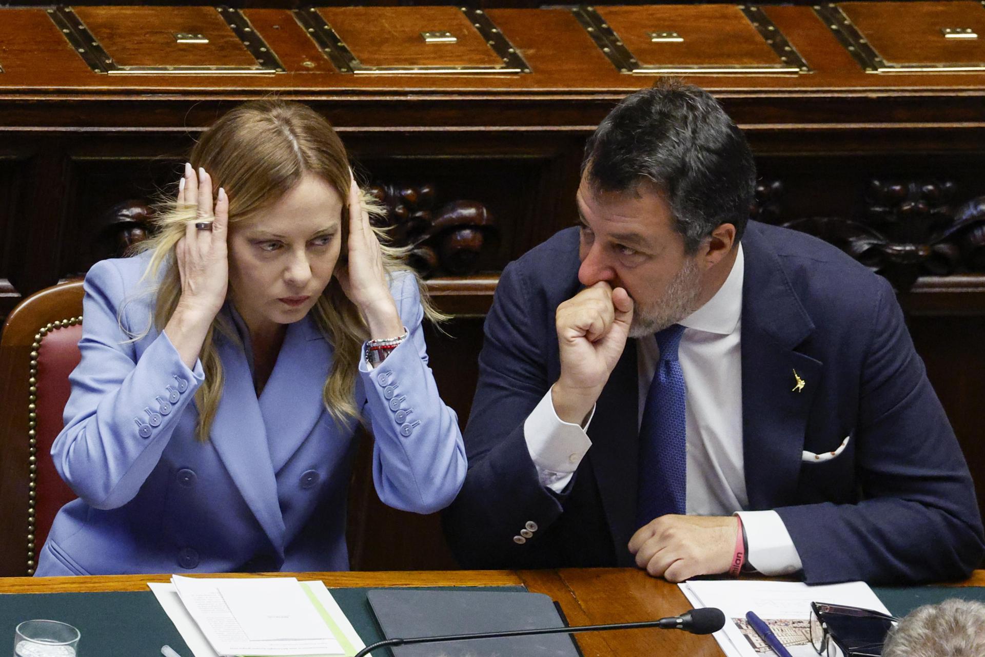 La primera ministra italiana Giorgia Meloni (i) habla con ministro de Infraestructuras y Transportes y viceprimer ministro italiano Matteo Salvini (d), este jueves durante una comparecencia ante la Cámara de Diputados sobre la próxima reunión del Consejo Europeo, en Roma, Italia. EFE/EPA/FABIO FRUSTACI
