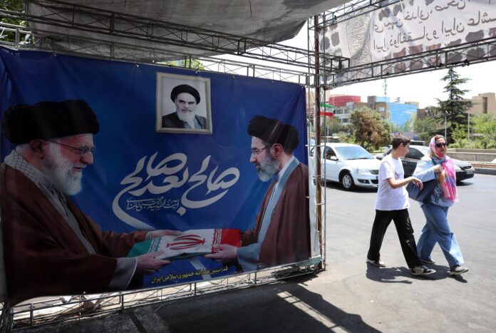 Iraníes pasan junto a un cartel del difunto líder supremo iraní Alí Jameneí (I) junto a su hijo y sucesor, Mojtaba Jameneí, en Teherán, Irán, el 11 de junio de 2026. Irán afirmó este jueves que los últimos ataques estadounidenses contra su territorio 