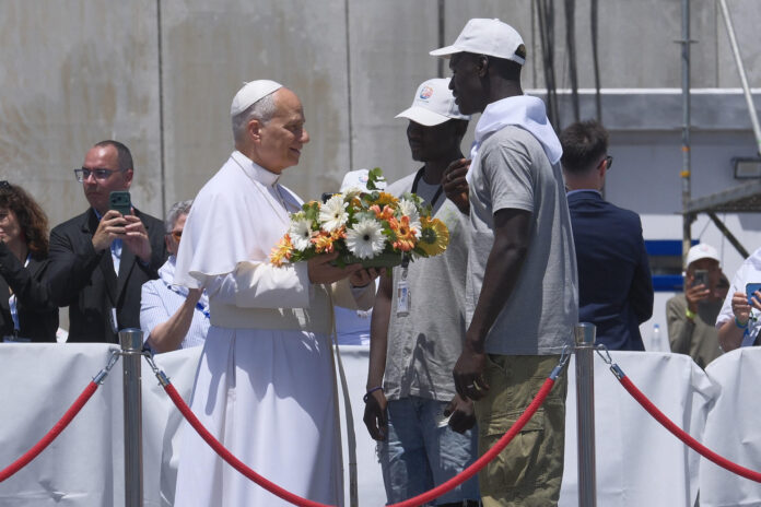 - El papa León XIV recibe flores de dos voluntarios para protagonizar una ofrenda floral en el mar en recuerdo de los migrantes muertos en la travesía durante el encuentro con más de un millar de inmigrantes de África, América Latina y con representantes de las principales instituciones y organizaciones sociales que trabajan en los servicios de rescate, acogida e integración en el muelle de Arguineguín, en la isla de Gran Canaria, este jueves, en el sexto día de su viaje a España. EFE/ Angel Medina G. POOL
