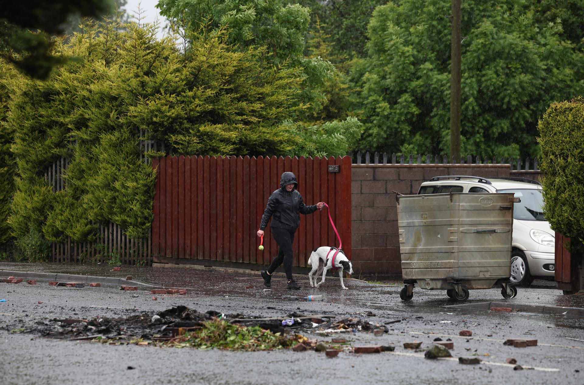 - Un paseador de perros pasa entre escombros tras una noche de disturbios violentos en Antrim Road, Newtownabbey, Irlanda del Norte, 11 de junio de 2026. Los manifestantes antiinmigración incendiaron, dañaron propiedades y atacaron a la policía durante una segunda noche de violencia tras un apuñalamiento en Belfast. Hadi Alodid, de treinta años y nacionalidad sudanesa, ha sido acusado de intento de asesinato tras un apuñalamiento en Belfast el 8 de junio. (Irlanda, Reino Unido) EFE/EPA/ADAM VAUGHAN
