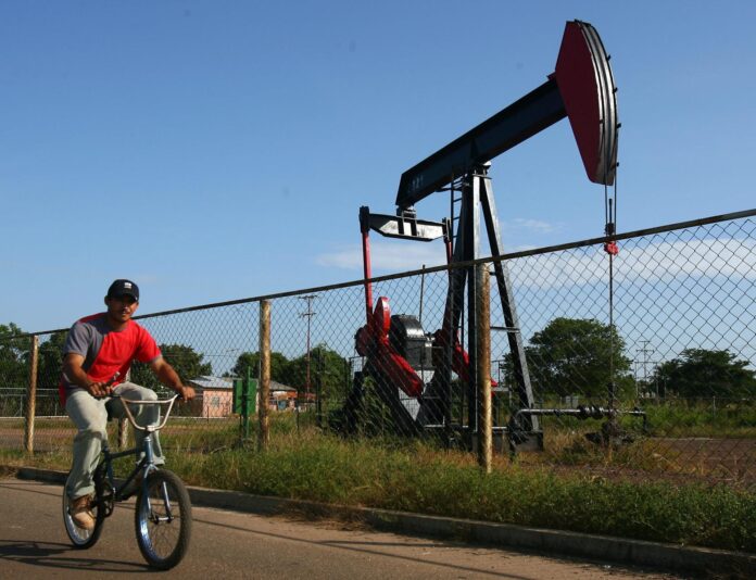 Fotografía de archivo de un hombre en bicicleta al pasar cerca de un pozo petrolero en la Costa Oriental del Lago de Maracaibo (Zulia, Venezuela). EFE/Eduardo Morales
