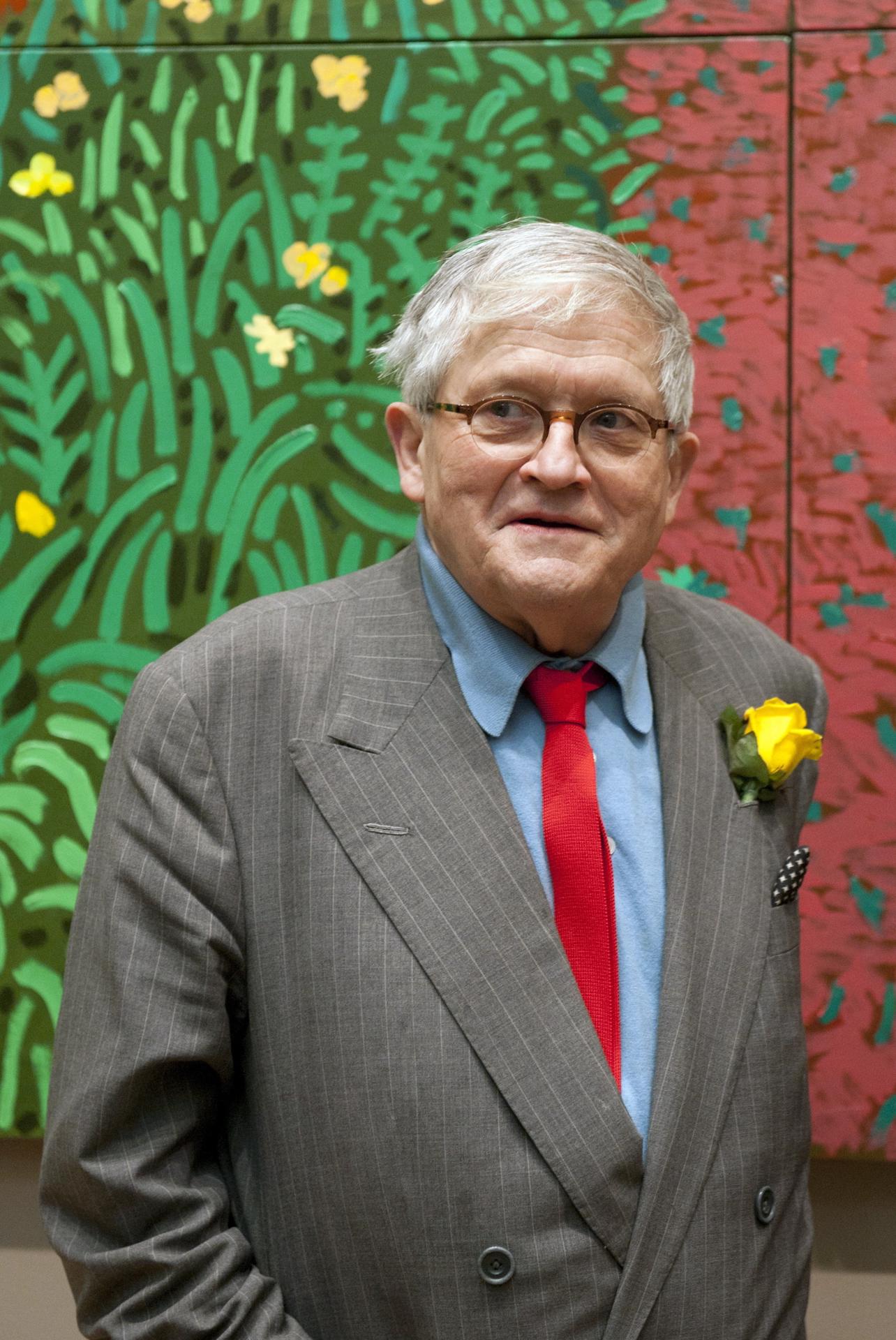 Una imagen de archivo fechada el 16 de enero de 2012 (reeditada el 12 de junio de 2026) muestra al artista británico David Hockney posando para fotógrafos con su pintura "La llegada de la primavera a Woldgate, East Yorkshire en 2011" en su exposición "A Bigger Picture" en la Royal Academy de Londres, Gran Bretaña. David Hockney falleció a los 88 años el 11 de junio de 2026. EFE/EPA/FACUNDO ARRIZABALAGA
