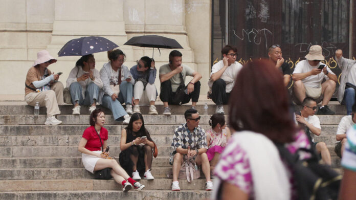 Turistas se refugian con paraguas y gorros en las escaleras de la Opéra de París, en plena ola de calor, en una imagen de archivo. EFE/ Edgar Sapiña
