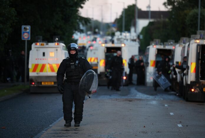 Un agente de policía camina con equipo antidisturbios en el lugar de los disturbios antiinmigración en Antrim Road en Newtownabbey, al norte de Belfast, Irlanda del Norte, el jueves 10 de junio de 2026. (Irlanda, Reino Unido) EFE/EPA/ADAM VAUGHAN
