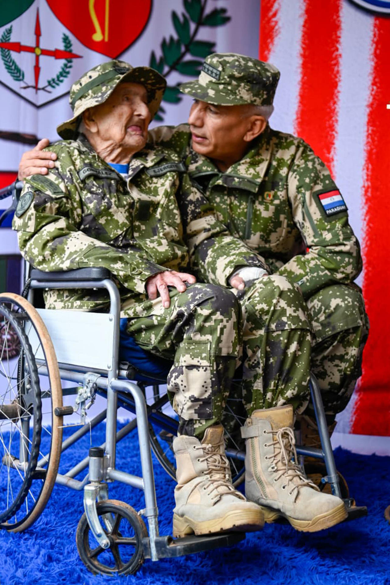 Fotografía cedida este 12 de junio por el Ministerio de Defensa de Paraguay en la que se captó al comandante del Ejército paraguayo, general Manuel Rodríguez (d), al hablar con el excombatiente de la Guerra del Chaco Canuto González (c), durante el aniversario 91 del Protocolo de Paz entre Paraguay y Bolivia, en San Lorenzo (Paraguay). EFE/Ministerio de Defensa de Paraguay

