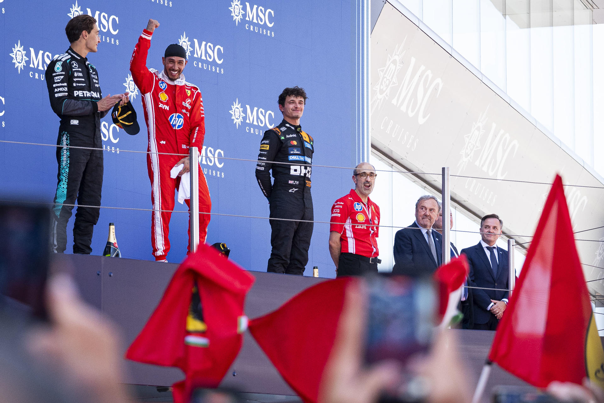 El piloto inglés del equipo Ferrari Lewis Hamilton, celebra en el podio su victoria tras imponerse en el Gran Premio de Barcelona-Cataluña de Fórmula 1, junto a los ingleses George Russell (i), del equipo Mercedes, segundo, y Lando Norris, del equipo McLaren (3i), tercero, este domingo en Barcelona. EFE/ Siu Wu
