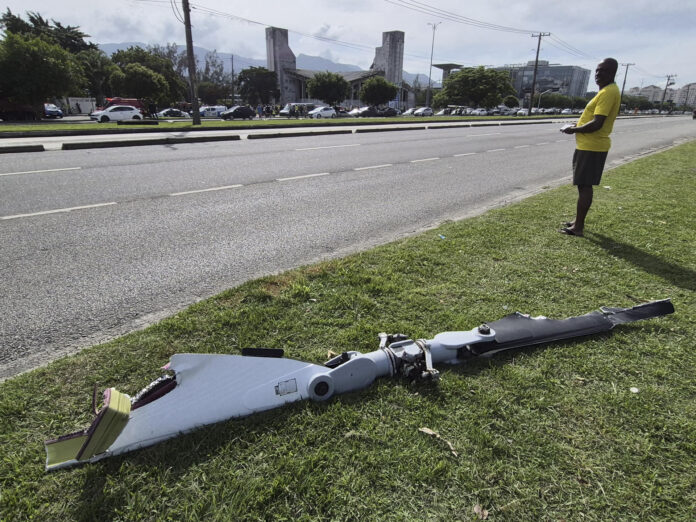 Fotografía cedida este 14 de junio por Roberta Durço que captó a una persona al observar un fragmento de uno de los dos helicópteros que colisionaron este domingo en el aire, en el barrio Recreio dos Bandeirantes, en Río de Janeiro (Brasil). EFE/Roberta Durço

