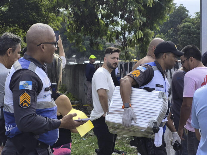 Fotografía cedida este domingo por Roberta Durço que muestra a un policía militar transportando una maleta recuperada en el lugar donde ocurrió el accidente de dos helicópteros en el barrio Recreio dos Bandeirantes, en Río de Janeiro (Brasil). EFE/ Roberta Durço
