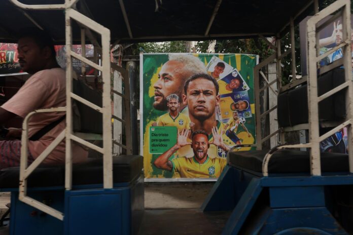 Un rickshaw pasa junto a un mural con imágenes de futbolistas brasileños en Howrah (Calcuta, India). EFE/PIYAL ADHIKARY
