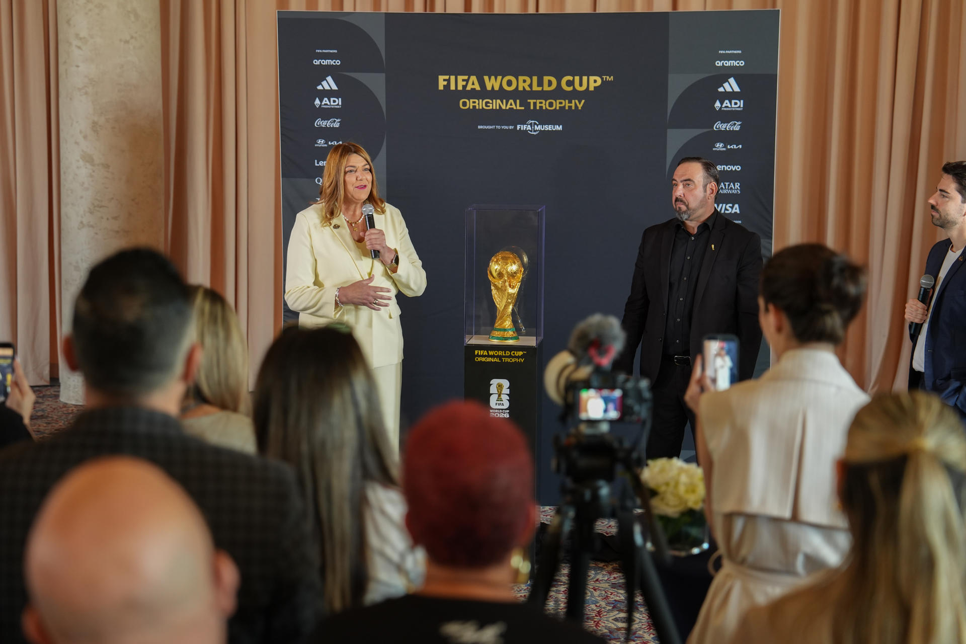 La presidenta del Miami-Dade College (MDC), Madeline Pumariega (i) y el director del Museo de la FIFA, Marco Fazzone (d), hablan junto a la Copa del Mundo FIFA este lunes, en Miami (Estados Unidos). La copa original del Mundial de la FIFA se exhibe de forma gratuita en la Torre de la Libertad (Freedom Tower) de Miami, que acoge ahora su primer partido del torneo, el de Arabia Saudí contra Uruguay, país latinoamericano que tiene su mayor comunidad en EE.UU. en esta ciudad. EFE/ Alberto Boal