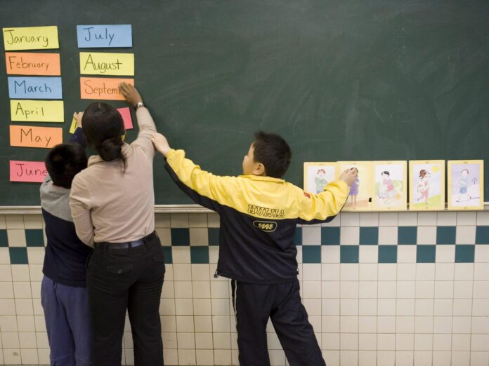 En la imagen de archivo, una profesora ayuda a unos alumnos de siete años en un aula de la Academia Huijia, un centro privado bilingüe de educación primaria, en las afueras de Pekín, China. EFE/Adrian Bradshaw
