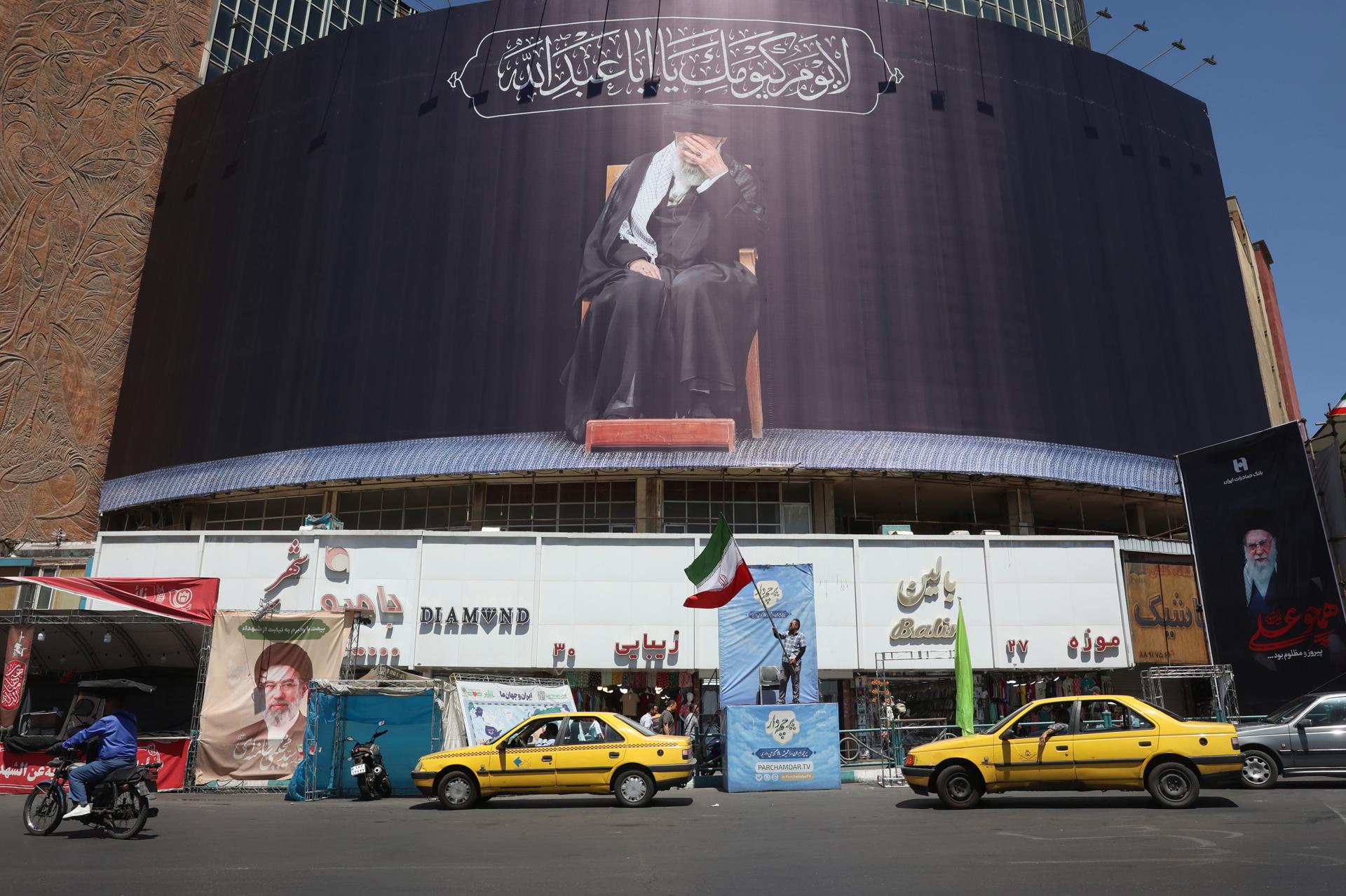 - Un iraní sostiene la bandera nacional de Irán junto a una valla publicitaria con el difunto líder supremo iraní, el ayatolá Alí Jamenei, en la plaza Valiasr de Teherán, Irán, el 15 de junio de 2026. El presidente de EE. UU., Donald Trump, anunció en su plataforma de redes sociales que se ha alcanzado un acuerdo con Irán y que se firmará el 19 de junio en Suiza. (Suiza, Teherán) EFE/EPA/ABEDIN TAHERKENAREH RESTRICCIONES: NO acceso a medios israelíes/emisoras de televisión en persa fuera de Irán/estricto NO acceso a BBC Persian/VOA Persian/Manoto TV/Iran International TV. (Según lo ordenado por la Dirección General de Medios Extranjeros de Irán) --
