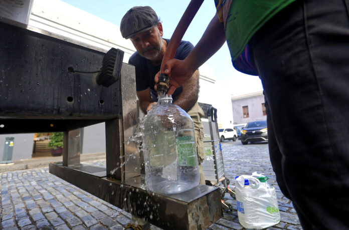 Personas se abastecen de agua tras la interrupción del servicio este lunes, en San Juan (Puerto Rico). EFE/Thais Llorca
