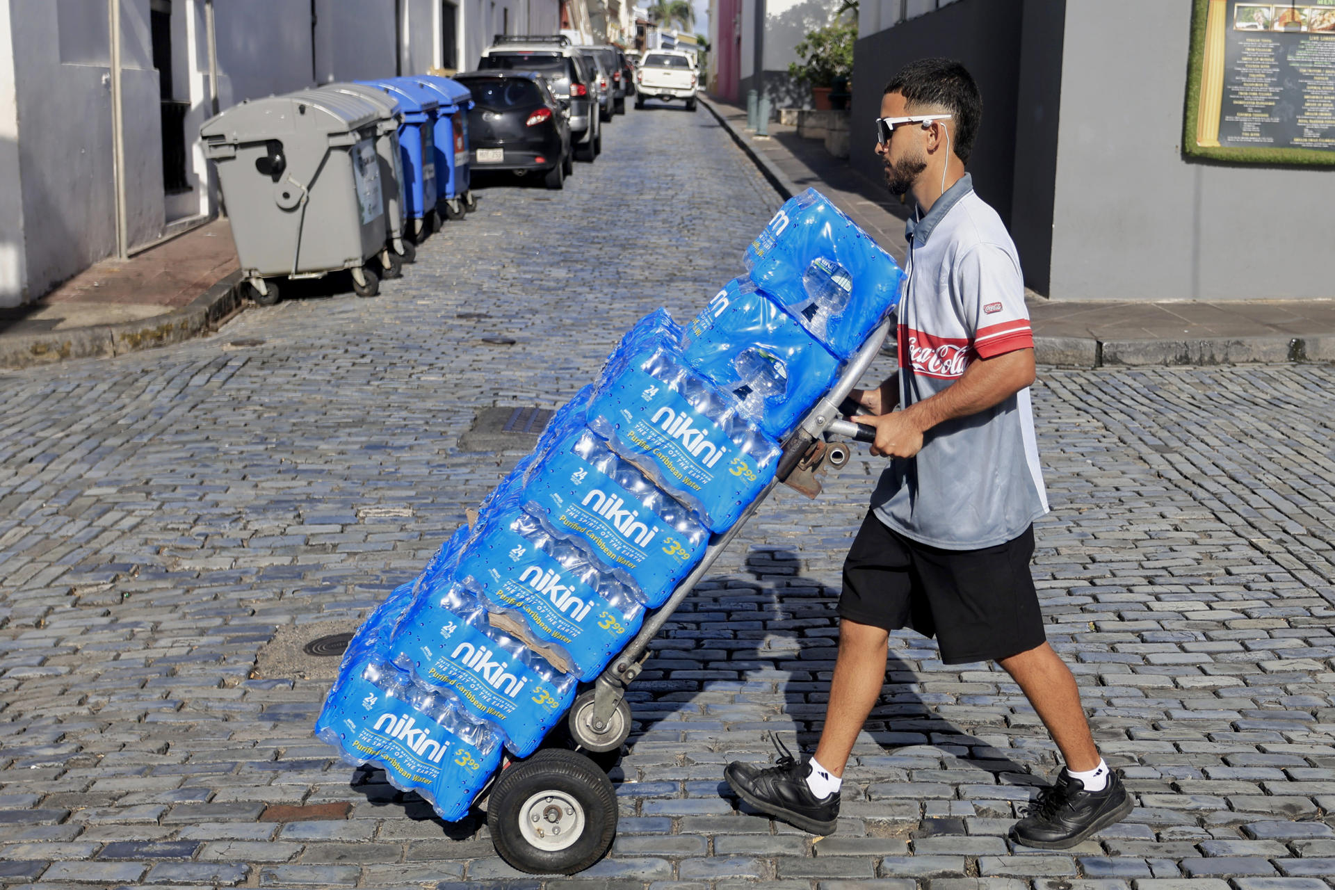 Un hombre transporta botellas de agua tras la interrupción del servicio este lunes, en San Juan (Puerto Rico). EFE/Thais Llorca

