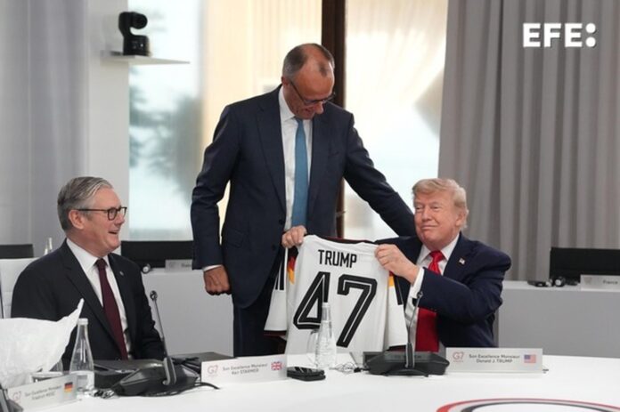 El presidente de Estados Unidos, Donald Trump (d), sostiene una camiseta de Alemania con su apellido y el número 47, junto al primer ministro británico, Keir Starmer (i), y el canciller alemán, Friedrich Merz (de pie), durante la cumbre del G7. EFE/ THIBAULT CAMUS / POOL *Prohibido su uso por MAXPPP*
