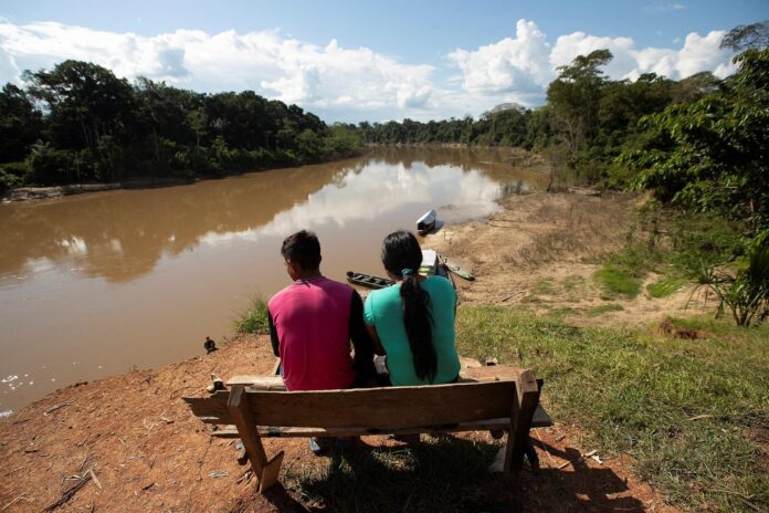 Fotografía de archivo que muestra a una pareja de indígenas del pueblo de Mayuruna cruiserinho, sentados en un banco a orillas del río Javari en Palmeiras do Javari, en la frontera con Perú. EFE/ Joédson Alves/ Archivo
