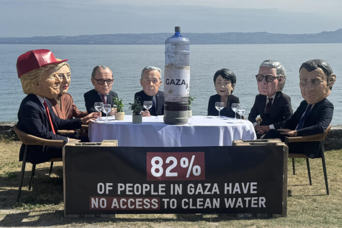 Siete activistas con máscaras que recreaban a los siete líderes del G7 se sentaron este martes a orillas del lago Lemán y brindaron con agua contaminada cerca de donde se celebra la cumbre de Évian, un acto con el que la organización Oxfam Intermón protestó por la falta de acción de los más poderosos frente a las violaciones de derechos humanos en Gaza, incluida la escasez de agua potable. La acción de protesta es una de las que organiza la ONG estos días junto al centro donde cientos de periodistas de todo el mundo siguen la cumbre.-EFE/ Antonio Broto
