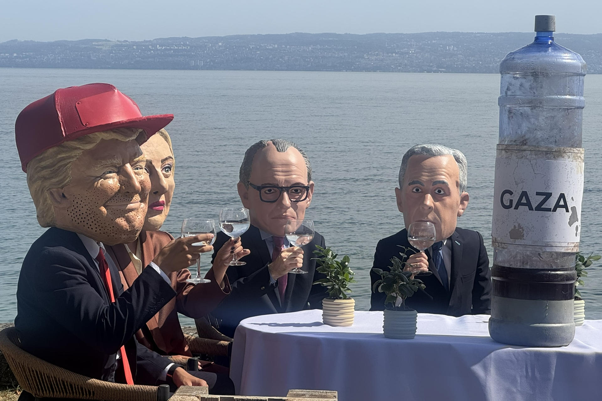 ÉVIAN (FRANCIA), 16/06/2026.- Siete activistas con máscaras que recreaban a los siete líderes del G7 se sentaron este martes a orillas del lago Lemán y brindaron con agua contaminada cerca de donde se celebra la cumbre de Évian, un acto con el que la organización Oxfam Intermón protestó por la falta de acción de los más poderosos frente a las violaciones de derechos humanos en Gaza, incluida la escasez de agua potable. La acción de protesta es una de las que organiza la ONG estos días junto al centro donde cientos de periodistas de todo el mundo siguen la cumbre.-EFE/ Antonio Broto
