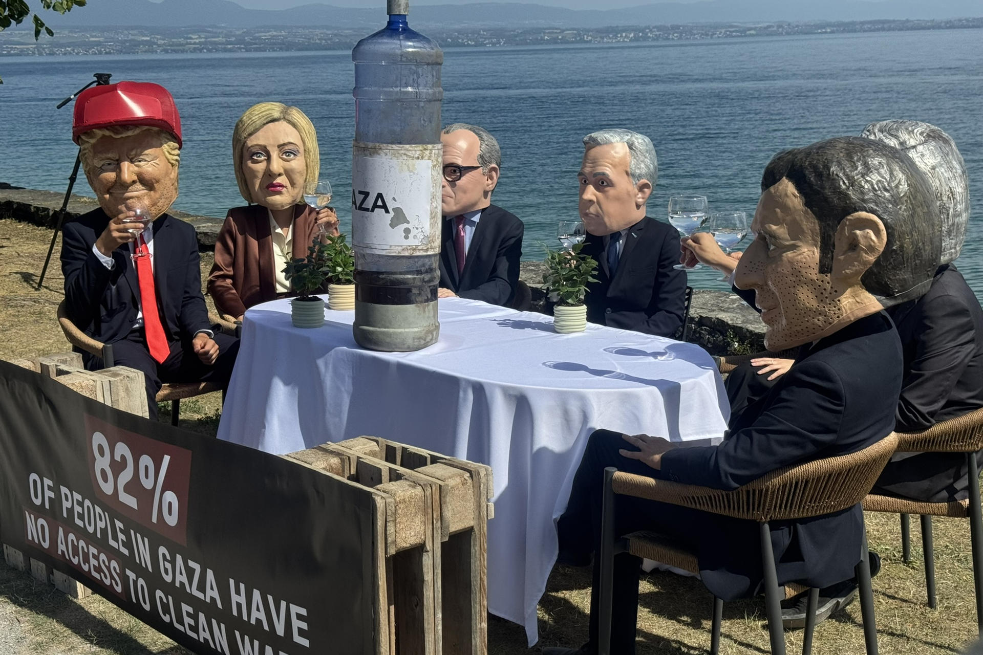 ÉVIAN (FRANCIA), 16/06/2026.- Siete activistas con máscaras que recreaban a los siete líderes del G7 se sentaron este martes a orillas del lago Lemán y brindaron con agua contaminada cerca de donde se celebra la cumbre de Évian, un acto con el que la organización Oxfam Intermón protestó por la falta de acción de los más poderosos frente a las violaciones de derechos humanos en Gaza, incluida la escasez de agua potable. La acción de protesta es una de las que organiza la ONG estos días junto al centro donde cientos de periodistas de todo el mundo siguen la cumbre.-EFE/ Antonio Broto
