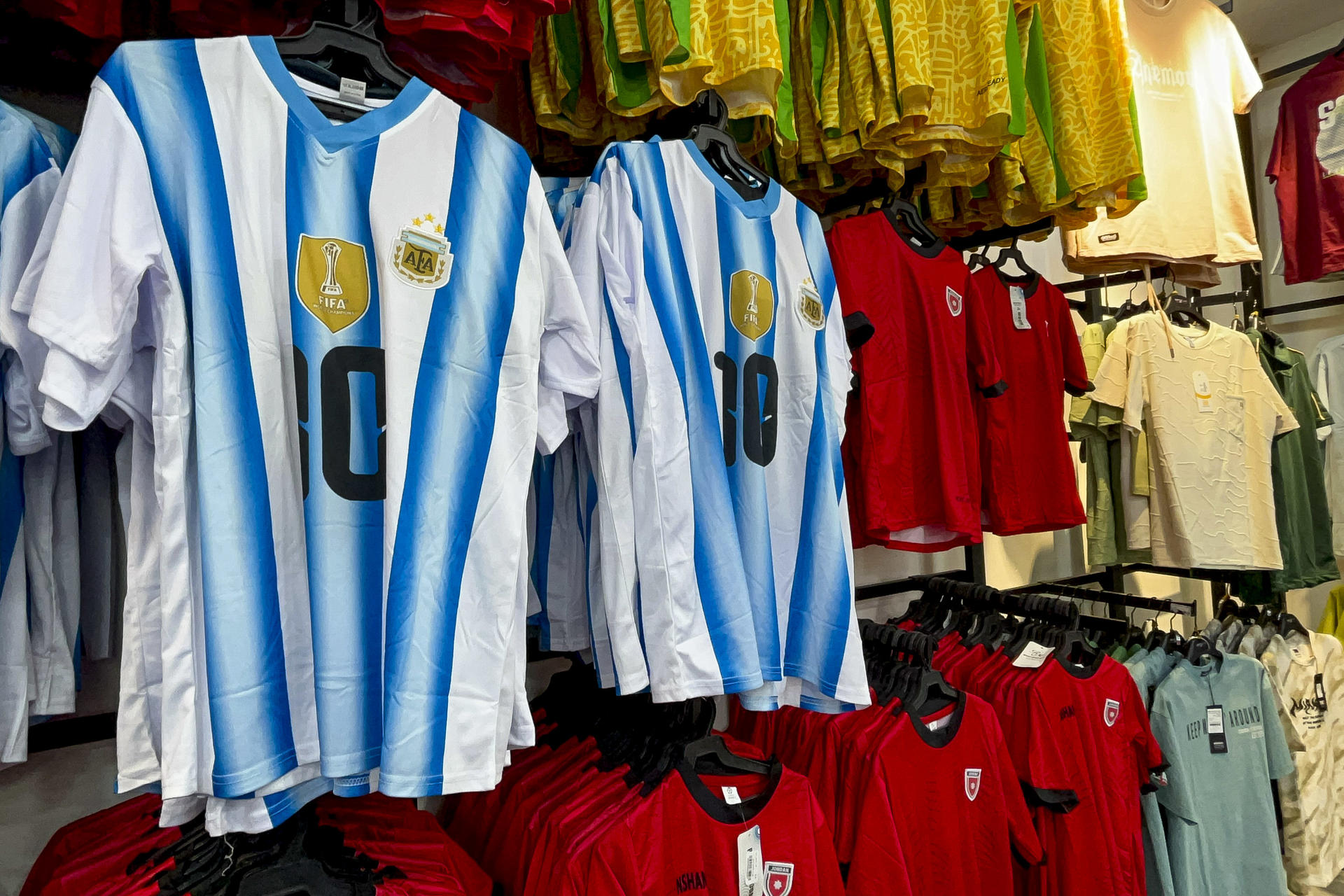 Camisetas de las selecciones argentina y jordana en una tienda de Jordania. Hajj Ibrahim, de 72 años, lleva décadas apoyando a Argentina en los mundiales de fútbol desde un café de Zarqa, al noreste de Amán (Jordania), pero en este Mundial su primer equipo será otro: el de su país, que mañana disputará el primer partido de su historia en la competición. Ibrahim sonríe al reconocer que le molesta "cuando alguien apoya a otra selección que no sea Argentina" y admite que, en esta ocasión, será él mismo quien reniegue de la Albiceleste durante el encuentro de fase de grupos que la enfrentará a la selección jordana el domingo 28 de junio.-EFE/ Hayat Al Dbeas