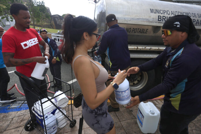 Un grupo de personas fue captado este 15 de junio al abastecerse de agua potable en San Juan (Puerto Rico), durante el mantenimiento al superacueducto que sirve a la isla. EFE/Thais Llorca
