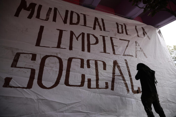 Un activista posa junto a un cartel durante una manifestación, donde acusan a las autoridades de intentar 