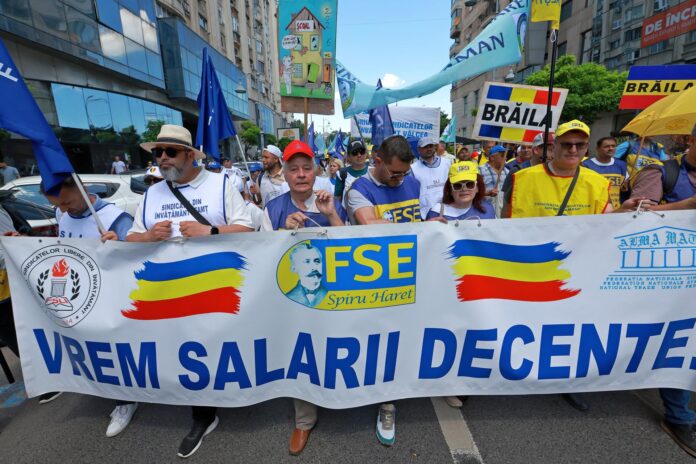 Profesores rumanos sostienen una pancarta que dice '¡Queremos salarios dignos!' mientras participan en una marcha de protesta convocada por sindicatos de educación, en Bucarest, Rumanía, 17 de junio de 2026. Miles de trabajadores sindicalizados del sector educativo de todo el país marcharon desde la sede del gobierno hasta el edificio del parlamento para exigir que un nuevo proyecto de ley salarial para el personal del sector público sea retirado del debate público. (Protestas, Rumanía, Bucarest) EFE/EPA/ROBERT GHEMENT
