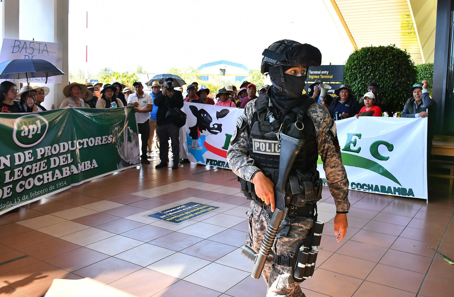 Un integrante de la policía custodia una protesta de productores de leche para exigir el fin de los bloqueos de carreteras en el país este miércoles, en el Aeropuerto Jorge Wilstermann en Cochabamba (Bolivia). EFE/Jorge Ábrego
