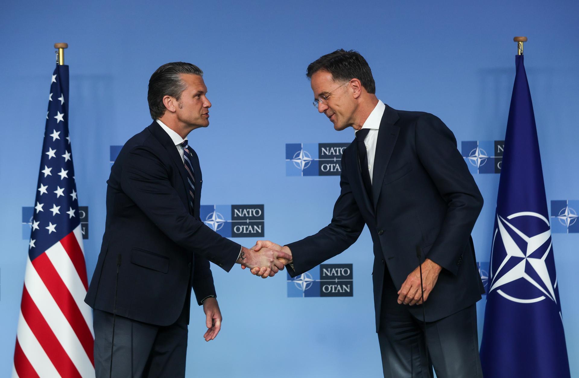 El secretario de Defensa de Estados Unidos, Pete Hegseth (i), estrecha la mano del secretario general de la OTAN, Mark Rutte (d), este jueves en una comparecencia antes de una reunión de los ministros de Defensa de la OTAN en la sede de la Alianza en Bruselas. EFE/EPA/Olivier Hoslet